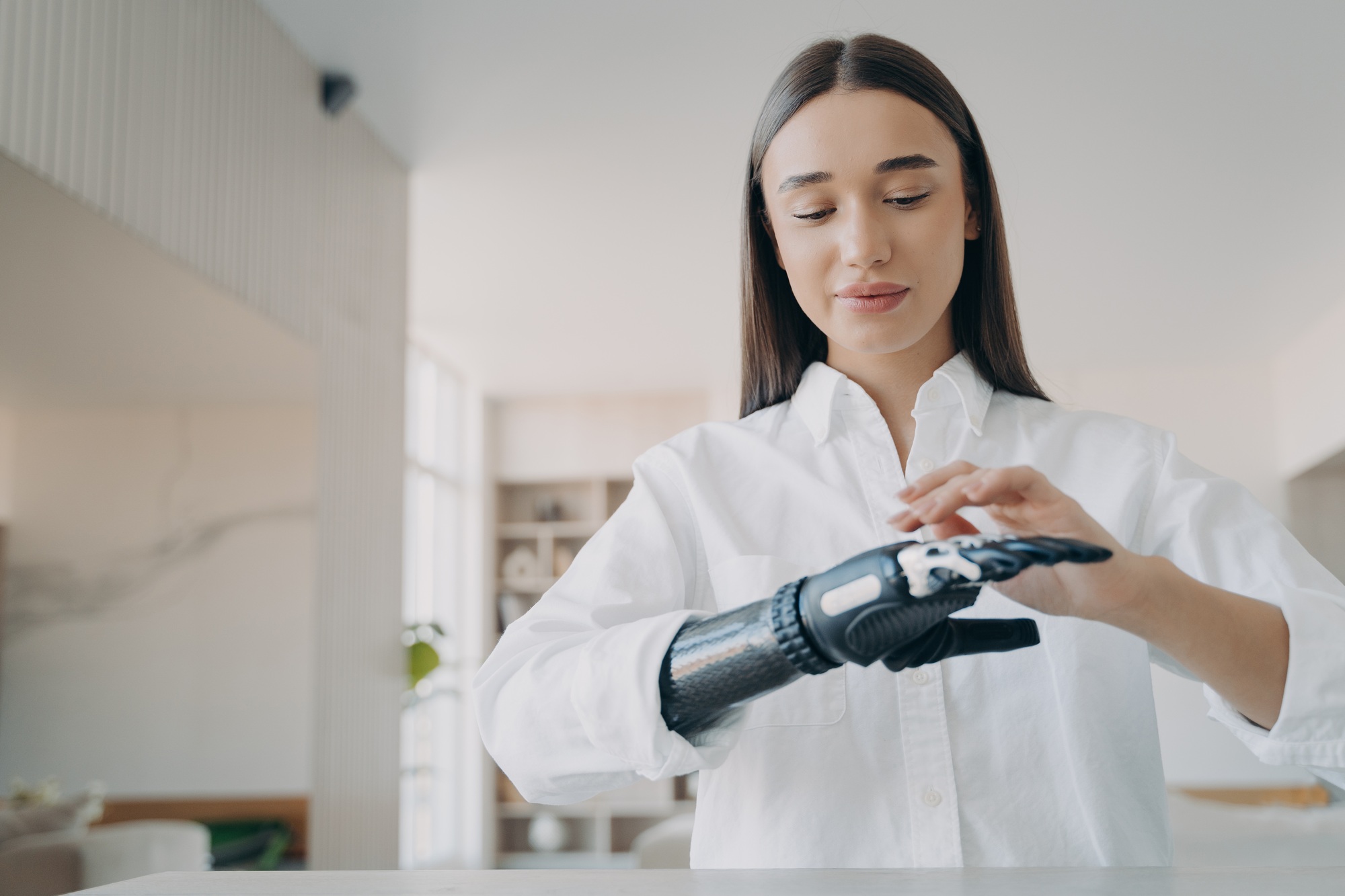 Happy handicapped girl is setting the prosthesis functions at home. Modern orthopedic technology.